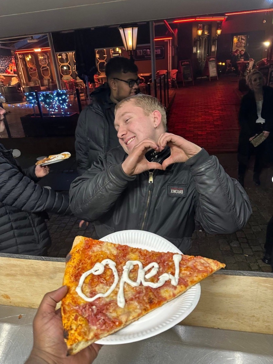 Glad gæst med en pizzaslice til et aftenarrangement